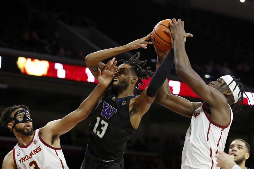 Washington forward Langston Wilson, center, reaches for the ball between Southern California forwards Chevez Goodwin, right, and Isaiah Mobley during the second half of an NCAA college basketball game in Los Angeles, Thursday, Feb. 17, 2022. (AP Photo/Alex Gallardo)
