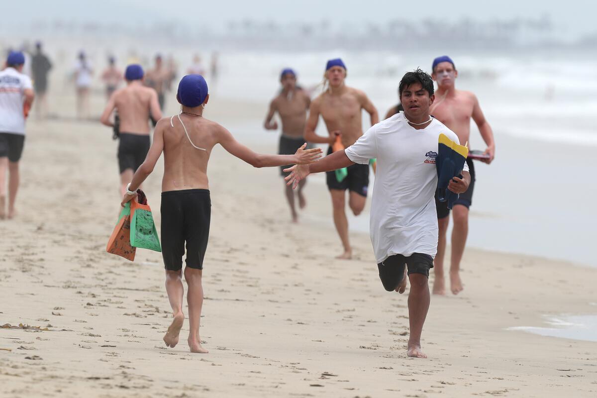 Huntington Beach junior lifeguards Chris Leon, 15, right, and Waylon Honnold, 13, left, high-five Thursday.