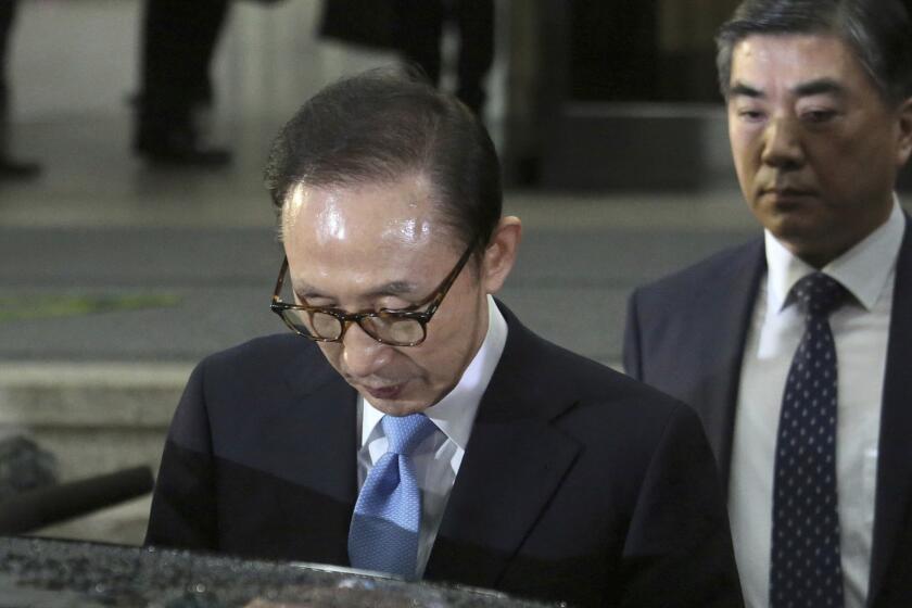 In this Thursday, March 15, 2018, photo, former South Korean President Lee Myung-bak, left, gets into a car to leave the Seoul Central District Prosecutors' Office in Seoul, South Korea. South Korean prosecutors said Monday, March 19, 2018 they have requested an arrest warrant for Lee over corruption allegations. (AP Photo/Ahn Young-joon)