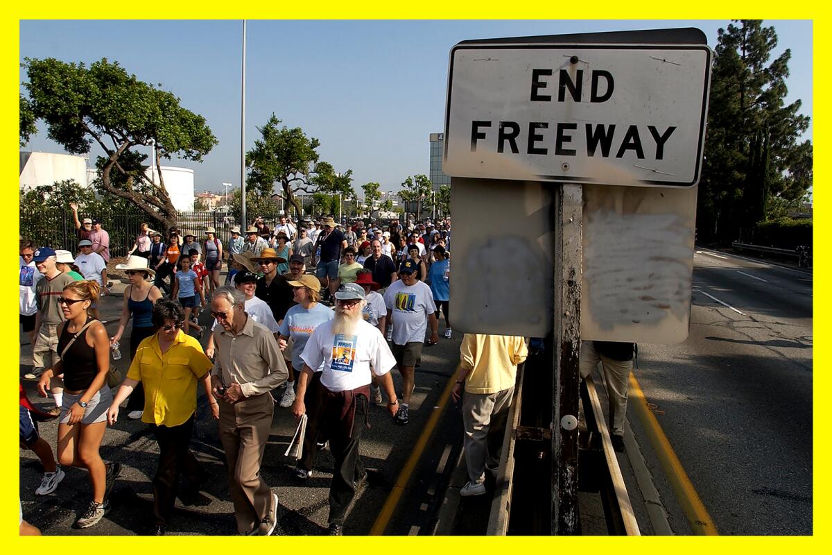 A large group of people walking past a sign that reads "end freeway"