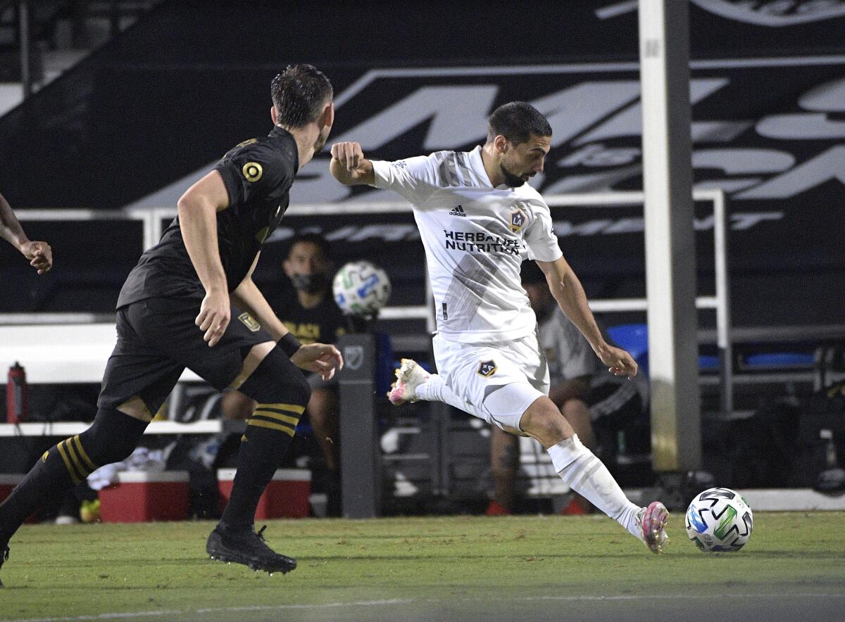 The Galaxy's Sebastian Lletget kicks the ball as LAFC's Mark-Anthony Kaye, far left, and Dejan Jakovic defend July 18.