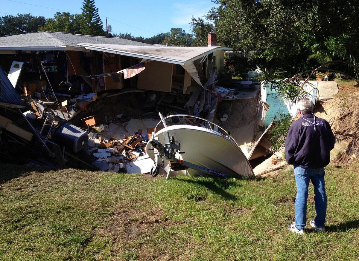 A man observes a sinkhole has swallowed parts of two houses in Dunedin, Fla. on Thursday, Nov. 14, 2013. Dunedin Deputy Fire Chief Trip Barrs said the hole appeared to be about 12-feet wide when officials arrived on the scene. Residents of the neighboring houses also were evacuated as a precaution. There are no reports of injuries. (AP Photo/The Tampa Tribune, Luke Johnson) ST. PETERSBURG OUT; LAKELAND OUT; BRADENTON OUT; MAGS OUT; LOCAL TV OUT; WTSP CH 10 OUT; WFTS CH 28 OUT; WTVT CH 13 OUT; BAYNEWS 9 OUT; THE TAMPA BAY TIMES OUT; LAKELAND LEDGER OUT; BRADENTON HERALD OUT; SARASOTA HERALD-TRIBUNE OUT; WINTER HAVEN NEWS CHIEF OUT ** Usable by LA and DC Only **