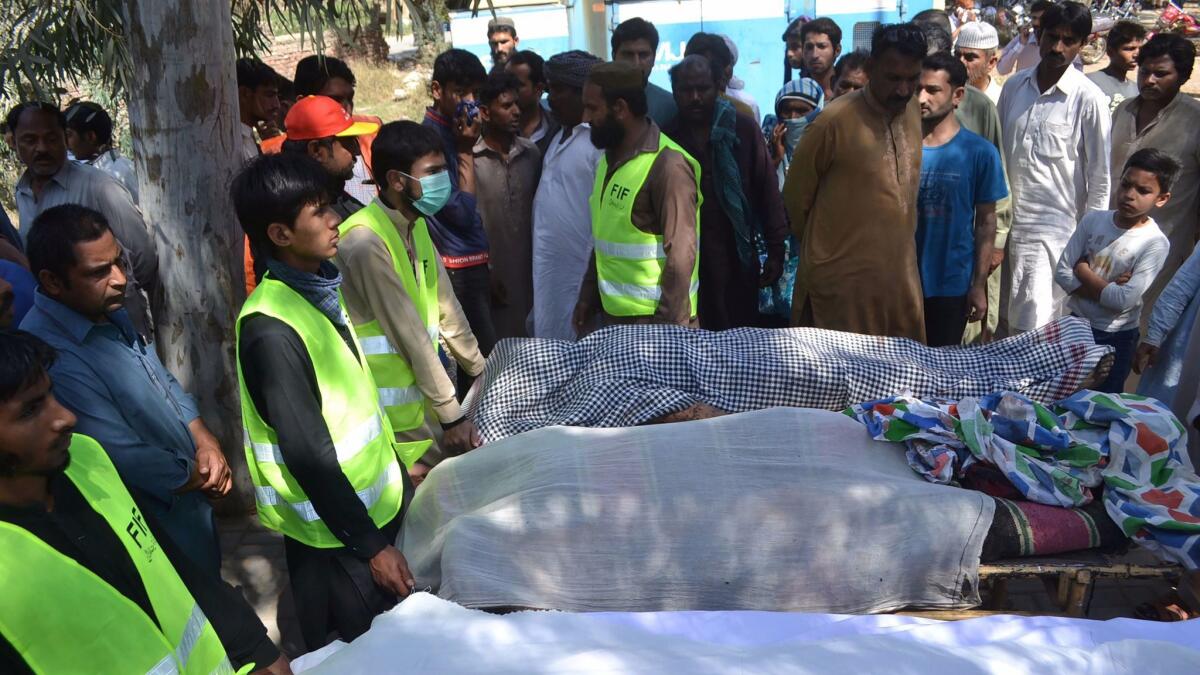 Volunteers wait to transport the bodies of people slain at a shrine near Sargodha, Pakistan.