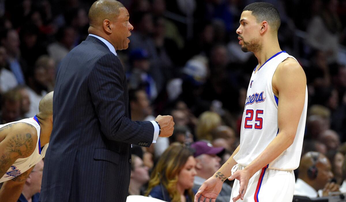 Clippers Coach Doc Rivers talks to his son, newly acquired guard Austin Rivers, as he leaves the court in the first half of their game against the Cavaliers.