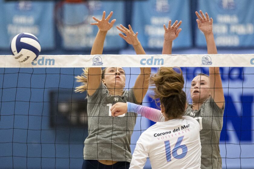 Newport Beach, CA - September 28: Newport Harbor's Sophia Kim, left, and Laine Briggs attempt to block a shot by Corona del Mar's Sabrina Baker during the Battle of the Bay girls' volleyball match on Wednesday, Sept. 28, 2022 in Newport Beach, CA. (Scott Smeltzer / Daily Pilot)