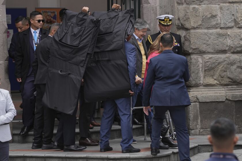 El presidente de Ecuador, Guillermo Lasso, está rodeado por agentes de seguridad cuando sale del Centro Cultural Metropolitano, ubicado junto al palacio presidencial en Quito, Ecuador, el jueves 30 de marzo de 2023. (AP Foto/Dolores Ochoa)