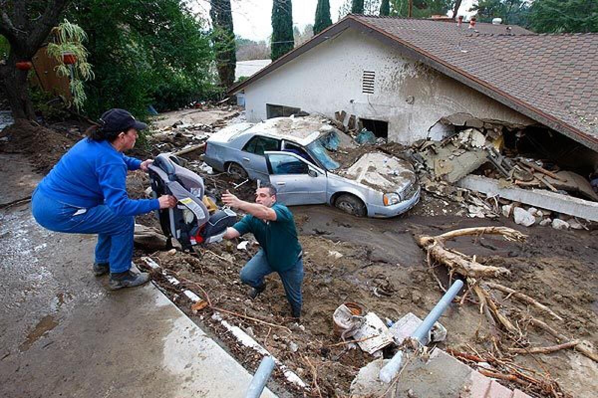 Danny Vartanian retrieved a child's car seat from Pat Anderson's car, which was swept down the embankment to a neighbor's house. Anderson, left, was on the second floor of her home when mud and debris surged through her house.