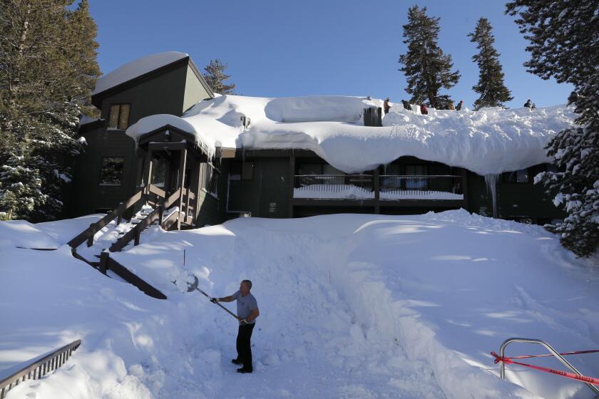 MAMMOTH LAKES, CALIF. -- WEDNESDAY, FEBRUARY 6, 2019: Erik Harriman, of Newport Beach, left, shovels the walkway as workers shovel giant snow drifts off the roofs of St. Anton condos in Mammoth Lakes after a blizzard dropped as much as 10 feet of snow in the biggest storm system so far this season Wednesday, Feb. 6, 2019. Mammoth Mountain was closed Tuesday because of the blizzard but reopened Wednesday. (Allen J. Schaben / Los Angeles Times)