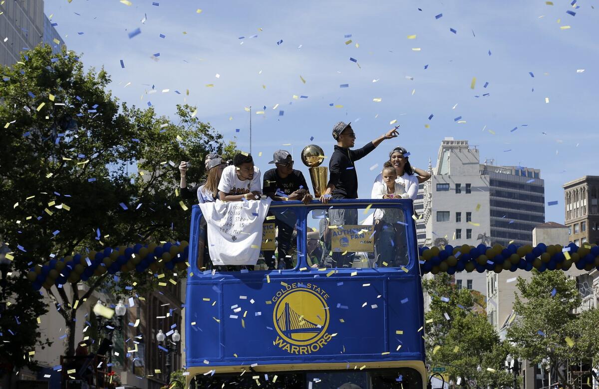 Golden State Warriors guard Stephen Curry, second from right, waves as he rides a bus during a parade for winning the NBA championship in Oakland. Three people were shot near the parade route.