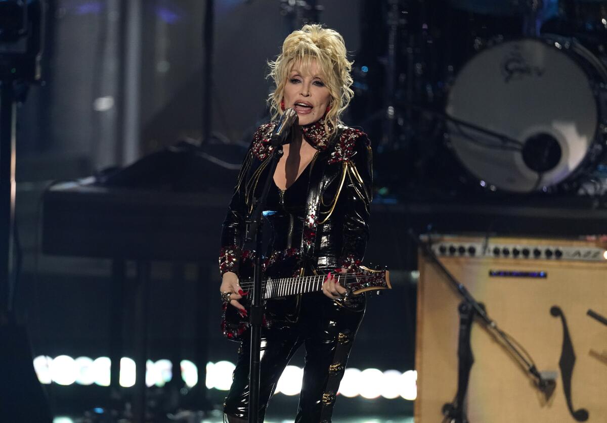 A female country singer/guitarist in a black leather catsuit performs onstage