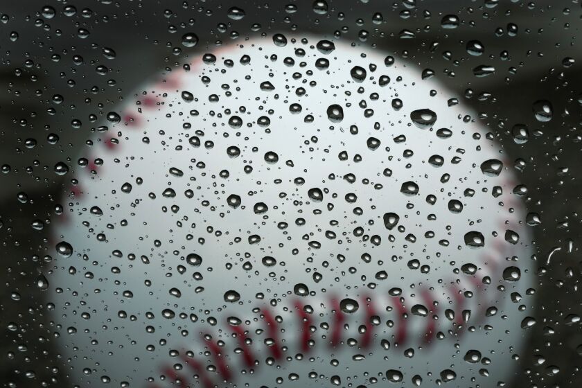 Una gran pelota hecha de concreto se aprecia a través de una ventaja con gotas de lluvia, en el complejo de pretemporada de los Marineros de Seattle, el martes 14 de febrero de 2023, en Peoria, Arizona (AP Foto/Charlie Riedel)