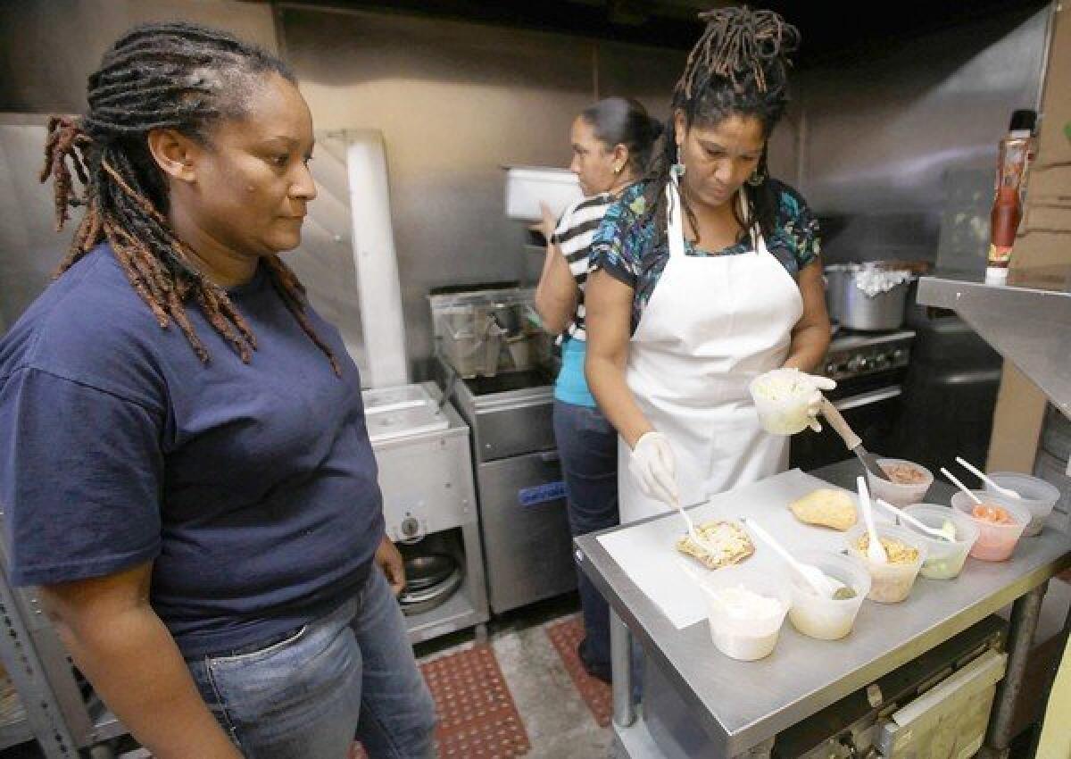 Ella's Belizean Restaurant offers takeout boxes of panades, salbutes and garnaches. Here owner Carla Dawson supervises the cooking of sister Connie.