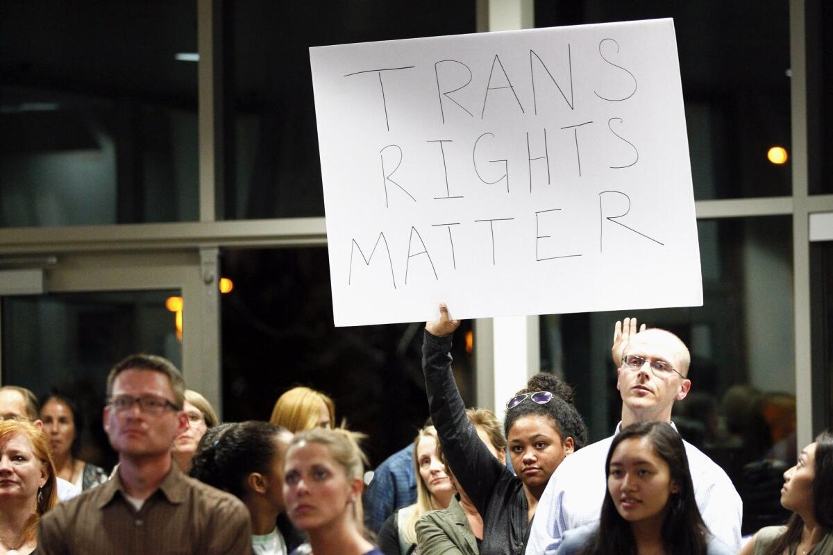 Morgan Smith, a senior at Francis Parker High School, holds a sign in favor of a transgender student's use of the boys locker room at RB High as she and an overflow crowd watch a Poway Unified School District board meeting from the lobby in San Diego on Tuesday.