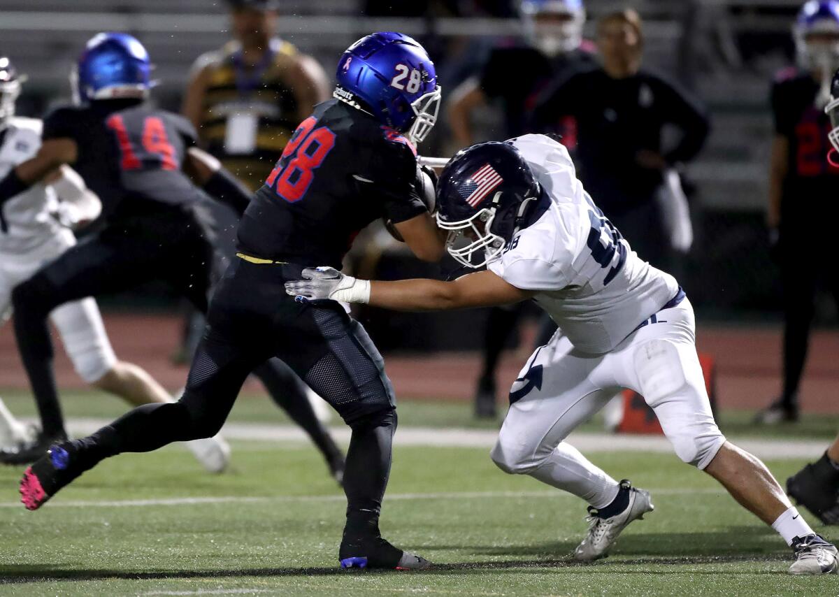 Newport Harbor's Mason Booth, right, brings down Lenny Ibarra at the line of scrimmage against Los Alamitos on Friday.