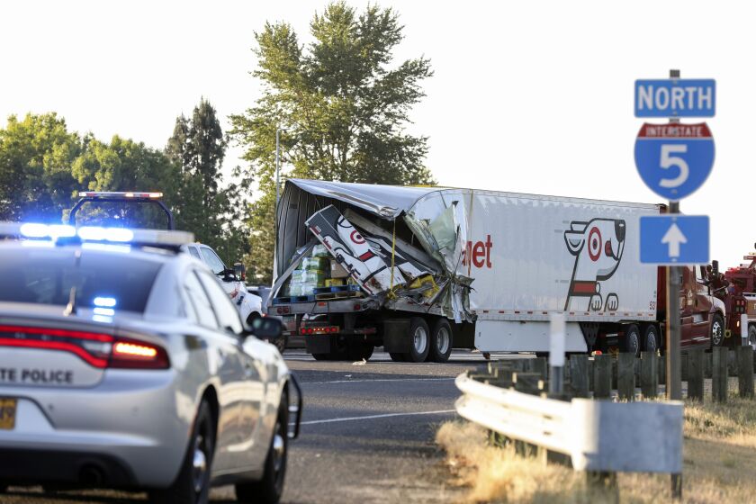 FILE - The back end of a semitruck sits along Interstate 5, Thursday, May 18, 2023, in Marion County, Ore. The semitruck driver involved in the crash on Interstate 5 earlier in the month that left seven farmworkers dead has been indicted on charges of manslaughter. Court documents show that a grand jury in Marion County Court on Tuesday, May 30, indicted Lincoln Smith on 12 counts, including manslaughter and driving under the influence. (Abigail Dollins/Statesman Journal via AP, File)