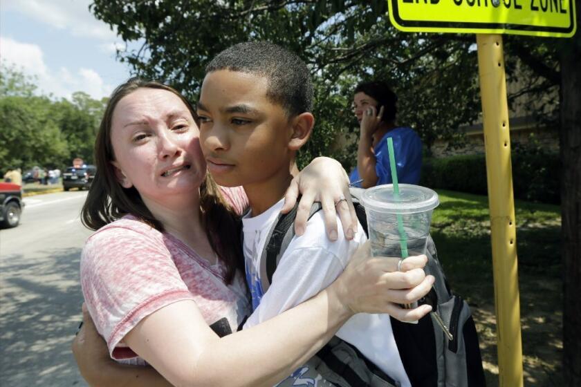 Lora Ross, left, hugs her son Jonathan Ross, 14, outside Spring High School in Spring, Texas. Students were dismissed after a 17-year-old student was stabbed to death and three others were injured in a fight at the Houston-area high school.