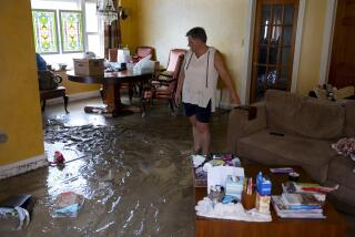 Ann Farkas walks in her flood-damaged home in Canisteo, N.Y., Friday, Aug. 9, 2024, after remnants of Tropical Storm Debby swept tough the area, creating flash flood conditions in some areas. (AP Photo/Craig Ruttle)