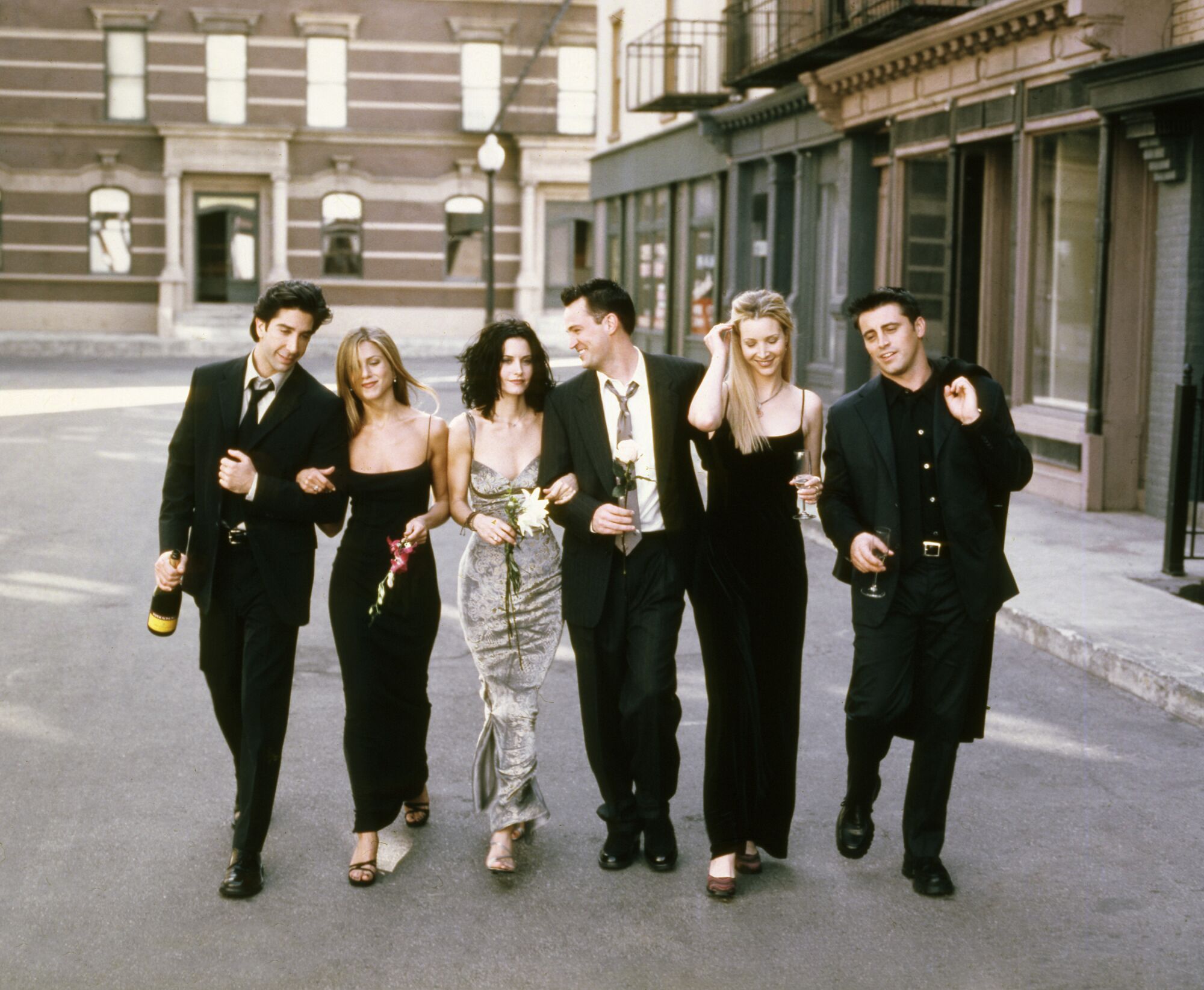 A group of people walks down a street for a portrait in formal attire.