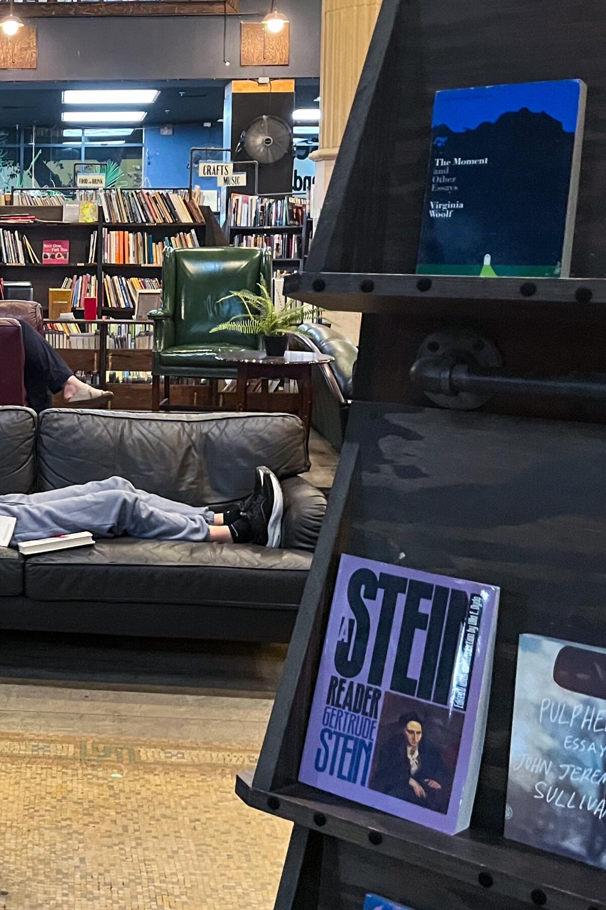 A person reads on a couch in the center of a bookstore.