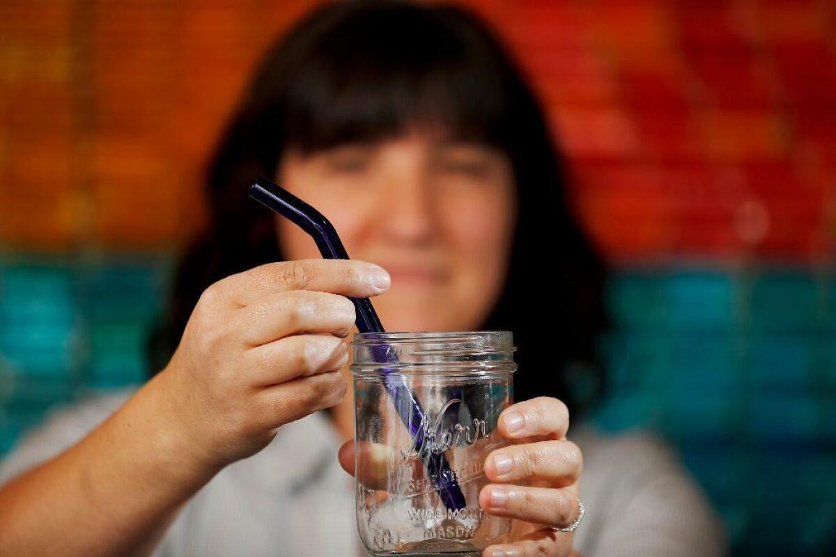 BYO Long Beach owner Julie Darrell with a reusable straw made of blue glass.