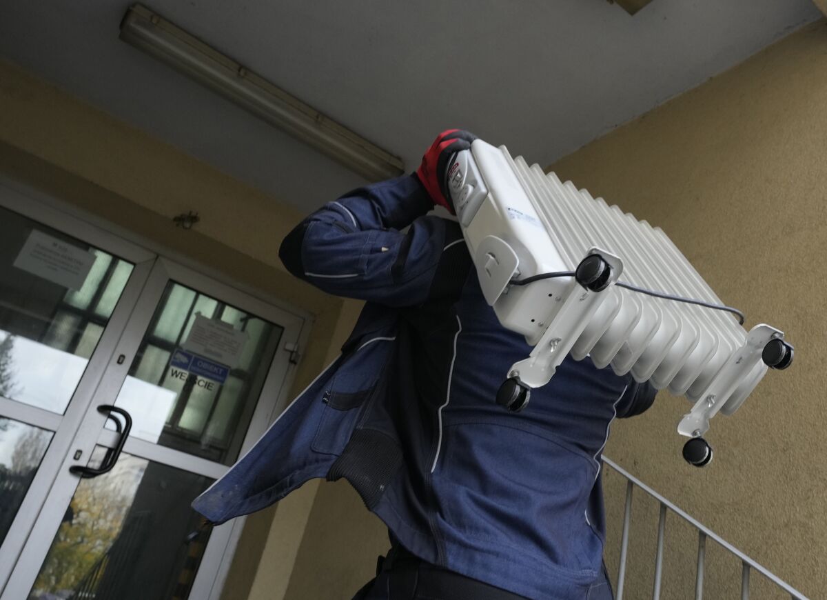 A man carries a heater into an apartment building in Warsaw, Poland, Oct. 27, 2021. Gas prices are soaring, leading some people to turn down their radiators and only heat individual rooms. Poland's central bank made its second interest rate hike in as many months on Wednesday as consumer prices surge. (AP Photo/Czarek Sokolowski)