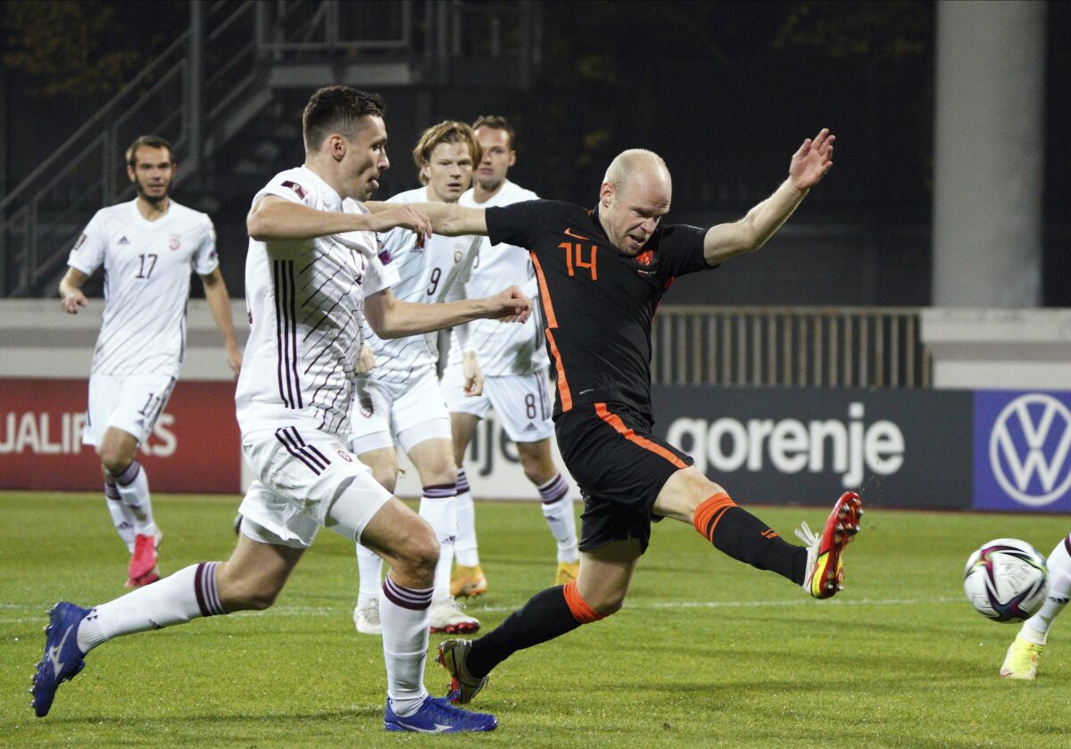 Latvia's Arturs Zjuzins, left, fights for the ball with Netherlands' Davy Klaassen during the World Cup 2022 group G qualifying soccer match between Latvia and the Netherlands at the Daugava stadium in Riga, Latvia, Friday, Oct. 8, 2021. (AP Photo/Roman Koksarov)