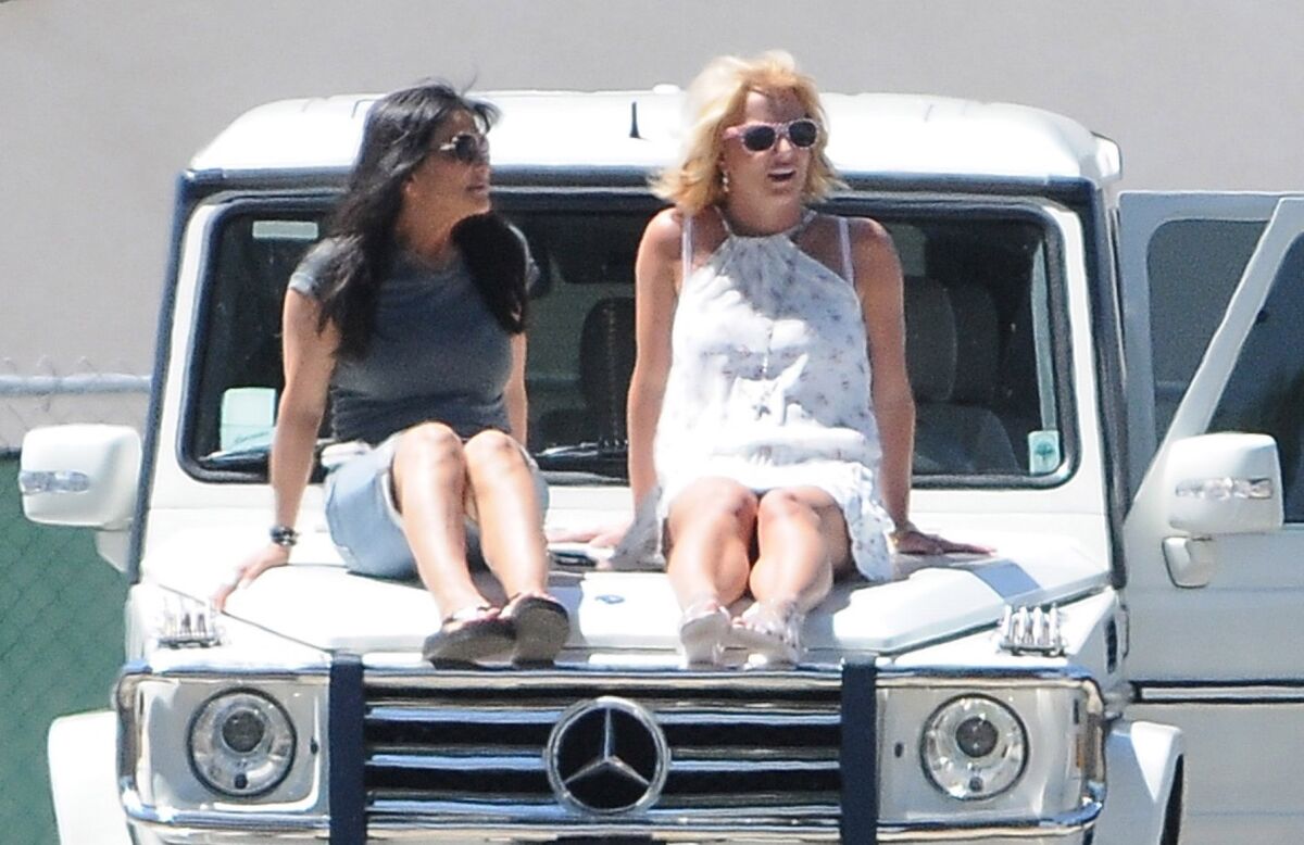 Lynne Spears and Britney Spears sit on the hood of a white Mercedes G Wagon