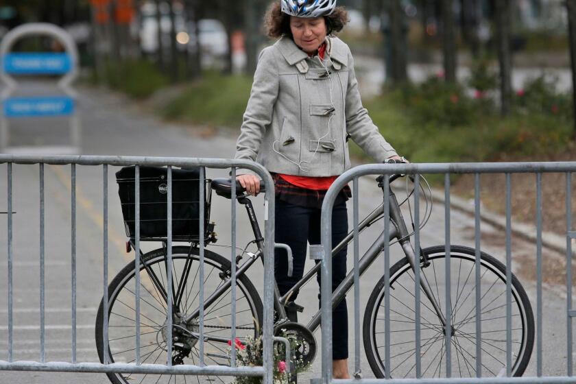 Celia Imrey pauses after laying flowers at the edge of a crime scene along the west side bike path in lower Manhattan, New York, Wednesday, Nov. 1, 2017. Investigators continue working to determine what led a truck driver to plow down people on a riverfront bike path near the World Trade Center, killing several, authorities said. (AP Photo/Seth Wenig)