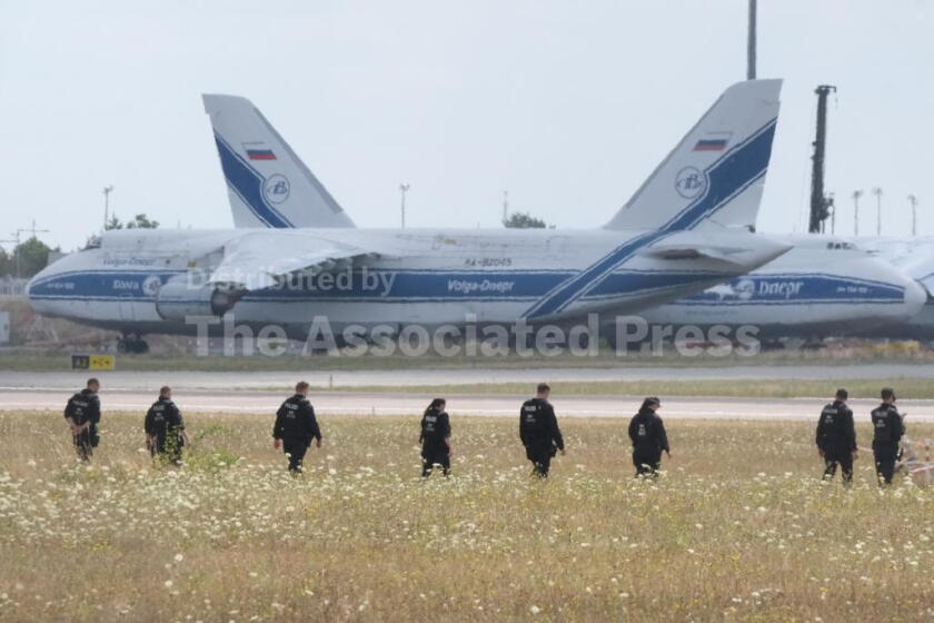 Police officers are walking across a field on the grounds of Leipzig Airport, in Schkeuditz, Germany, Friday, Aug. 7, 2026, searching for a drone that may be connected to a suspected attack. (Sebastian Willnow/dpa via AP)