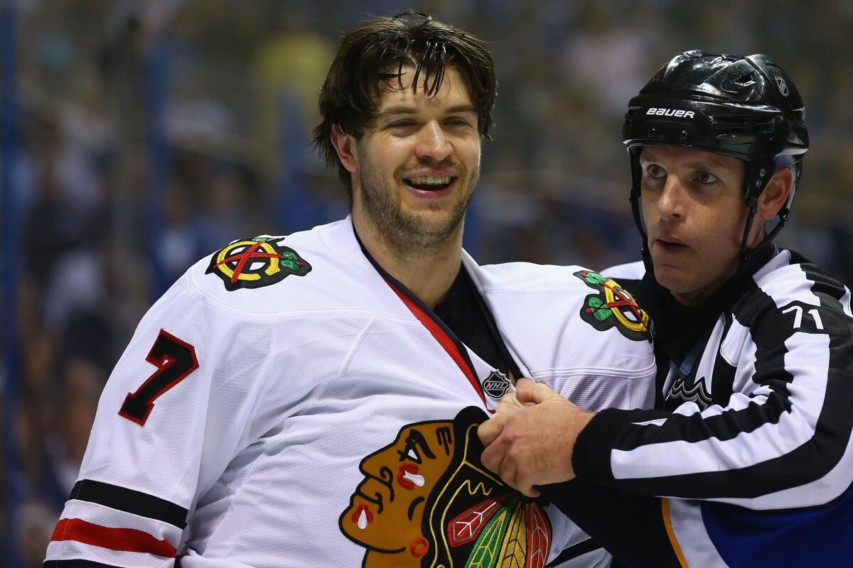 Blackhawks defenseman Brent Seabrook is restrained by referee Brad Kovachick after his hit to Blues center David Backes on Saturday in St. Louis.