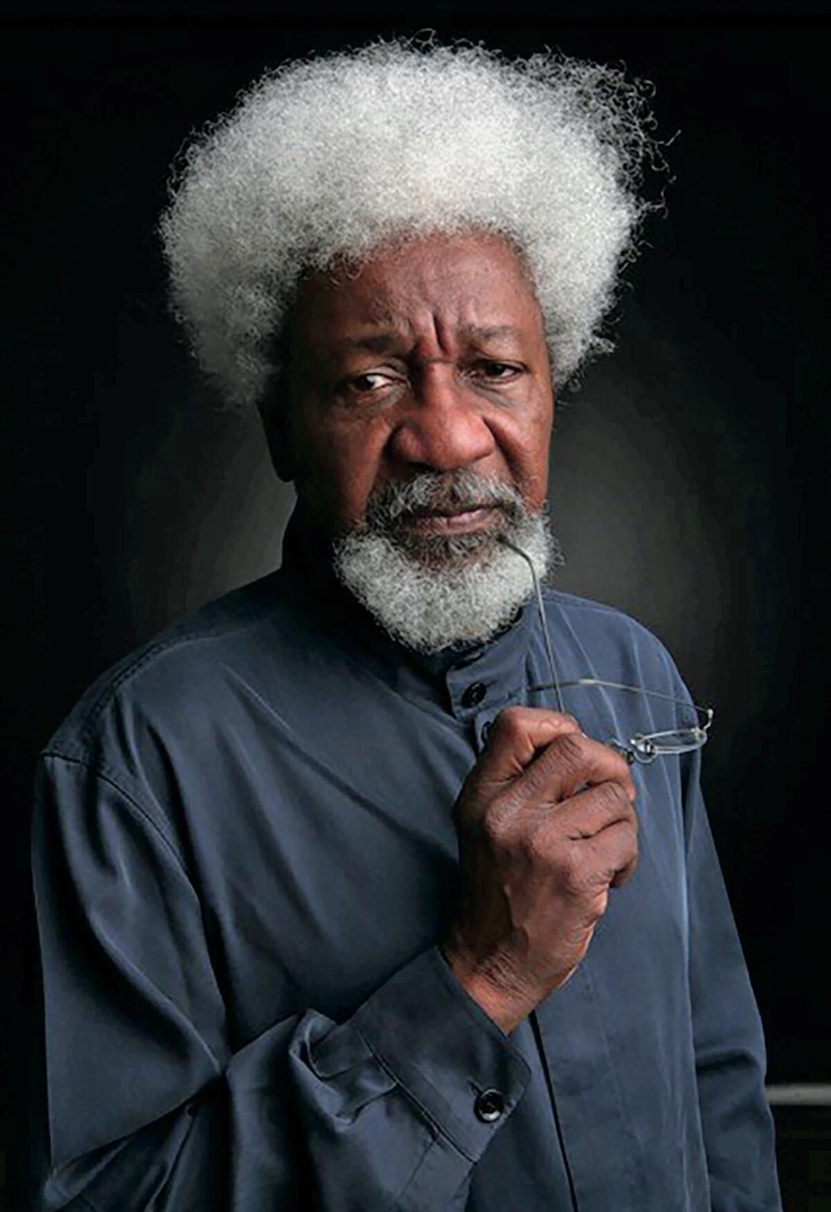 Nobel Prize winning writer Wole Soyinka, in a button-down shirt holding a pair of glasses in one hand.