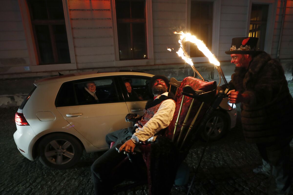 Members of the new circus company Cirk La Putyka entertain people driving through with their cars in Prague, Czech Republic, Saturday, Dec. 5, 2020. On the eve of St. Nicholas, Czechs traditionally celebrate by dressing up as Devils, Angels and St. Nicholas, and visiting children in their homes handing out small presents, coal, potatoes or other gifts. Due to government’s restrictive measures usual traditions would be impossible. A new circus company in Prague offered a solution Saturday. They invited the kids to drive with parents their in cars through the heaven and hell they created, with devils jumping in a distance and angels flying above them. The eager visitors formed a long line of cars at the La Putyka Circus base in Prague. (AP Photo/Petr David Josek)