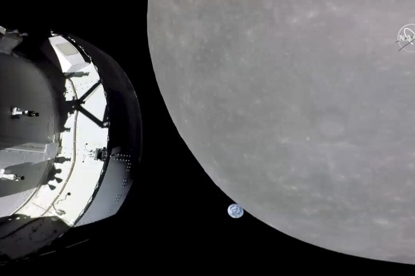 A screengrab from NASA TV shows NASA's Orion capsule nearing the moon on Monday, Nov. 21, 2022. At center is earth. 