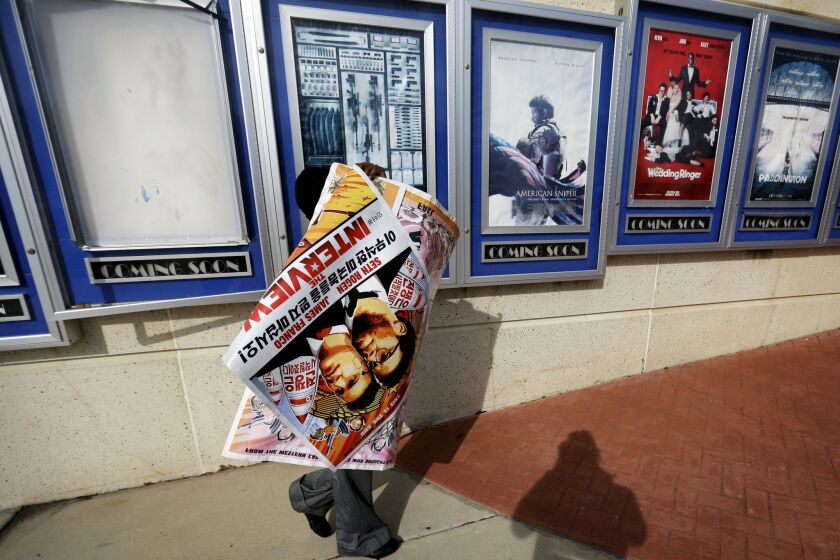 A poster for the movie "The Interview" is carried away by a worker after being pulled from a display case at a Carmike Cinemas movie theater in Atlanta on Dec. 17.