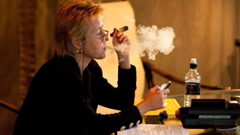 In 2009, Gov. Arnold Schwarzenegger's chief of staff at the time, Susan Kennedy, takes a break with a cigar in the smoking tent area of an outdoor courtyard at the governor's office at the state Capitol.