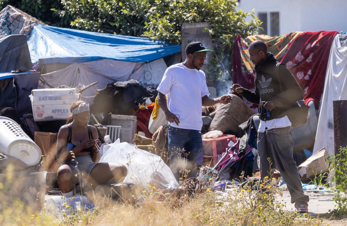 Homeless residents of a tent encampment pass the time as Inside Safe workers canvas the Los Angeles site.
