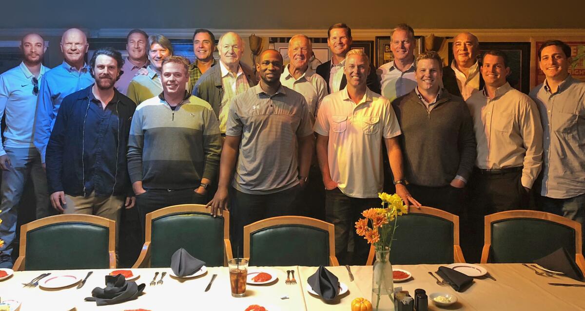 A group of former UCLA quarterbacks at a luncheon table.