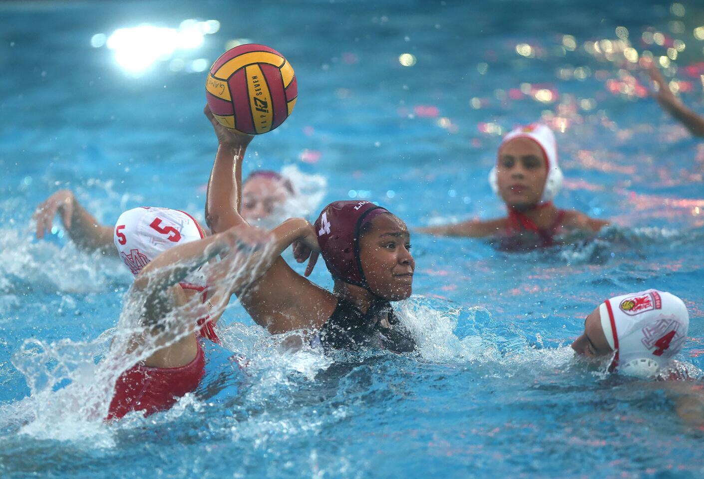 Imani Clemons (4) shoots under pressure during Laguna Beach High's nonleague water polo game against visiting Mater Dei on Friday.