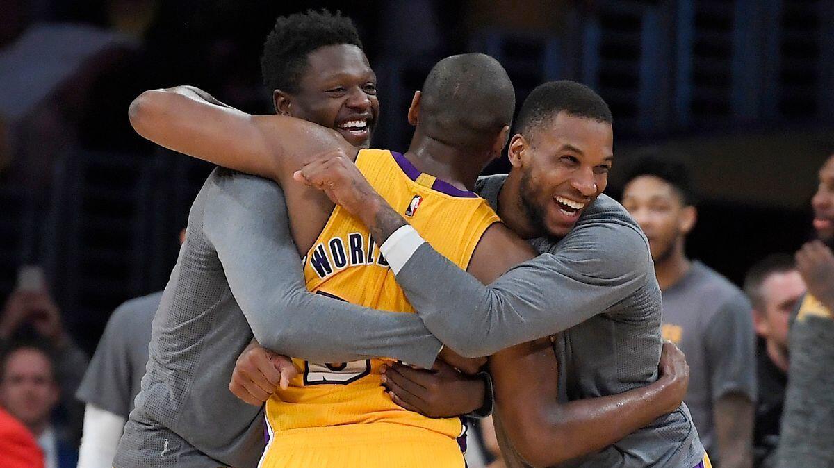 Lakers forward Metta World Peace, center, is hugged by forwards Julius Randle, left, and Thomas Robinson after the Lakers defeated the New Orleans Pelicans, 108-96.