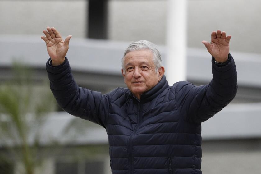 FILE - In this April 3, 2020 file photo, Mexican President Andres Manuel Lopez Obrador waves to supporters cheering from over an outside wall, after visiting a Mexican Social Security Institute (IMSS) hospital that will be converted to receive COVID-19 patients in the Coyoacan district of Mexico City. (AP Photo/Rebecca Blackwell, File)