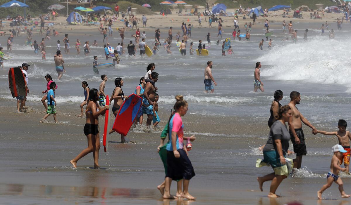 Hundreds of beachgoers play in the shore break at Corona del Mar State Beach on Tuesday.