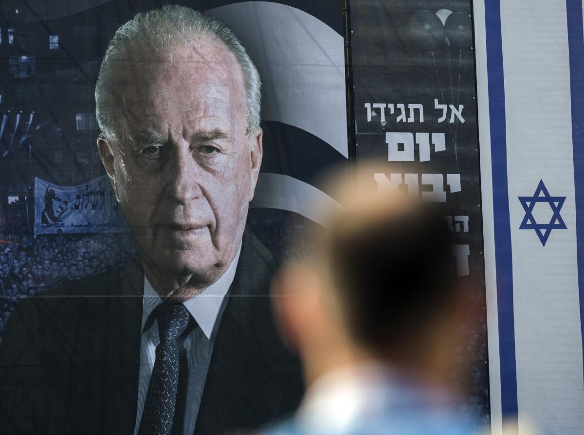 An Israeli man stands in front of a billboard bearing a portrait of late Israeli prime minister Yitzhak Rabin, ahead of a memorial rally marking the 20th anniversary of Rabin's assassination.