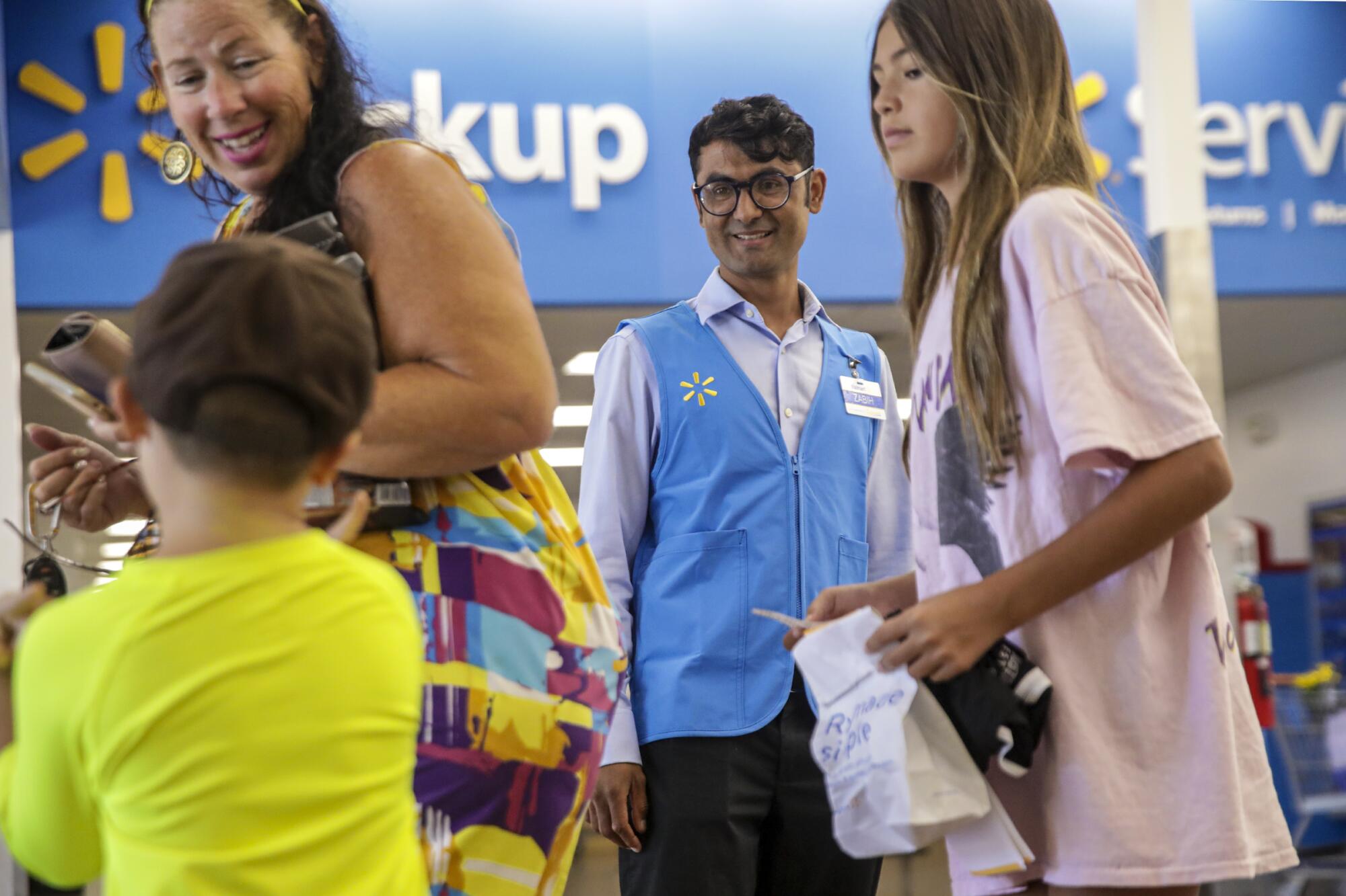 Zabih Khan, center, who fled Afghanistan with his 4-year-old brother, gets job training at Walmart in El Cajon.