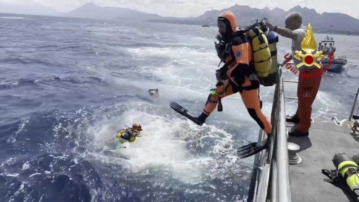 Scuba divers enter the water from a boat. 