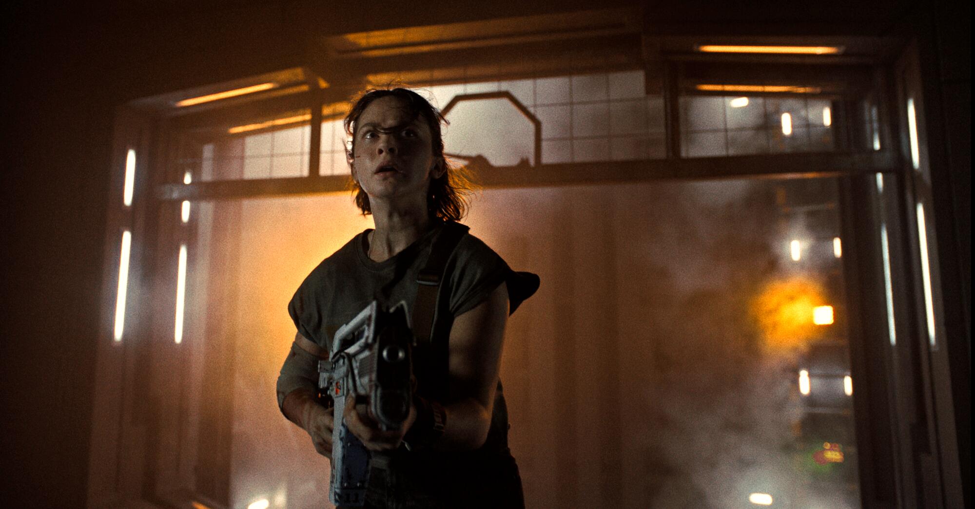 A woman patrols a spaceship with a weapon.