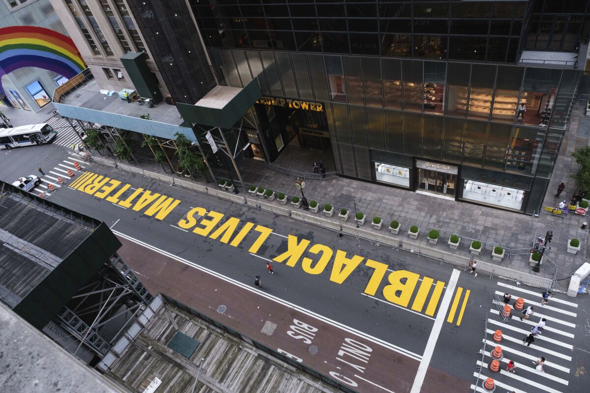 Pedestrians walk on a Black Lives Matter mural painted in front of Trump Tower, Friday, July 10, 2020, in New York. (AP Photo/Yuki Iwamura)