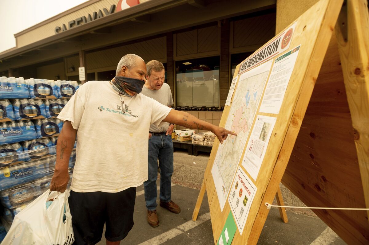 As evacuation orders take effect for the Dixie fire, Carlos Duran, left, and Rich McFeely examine a fire map in Quincy.