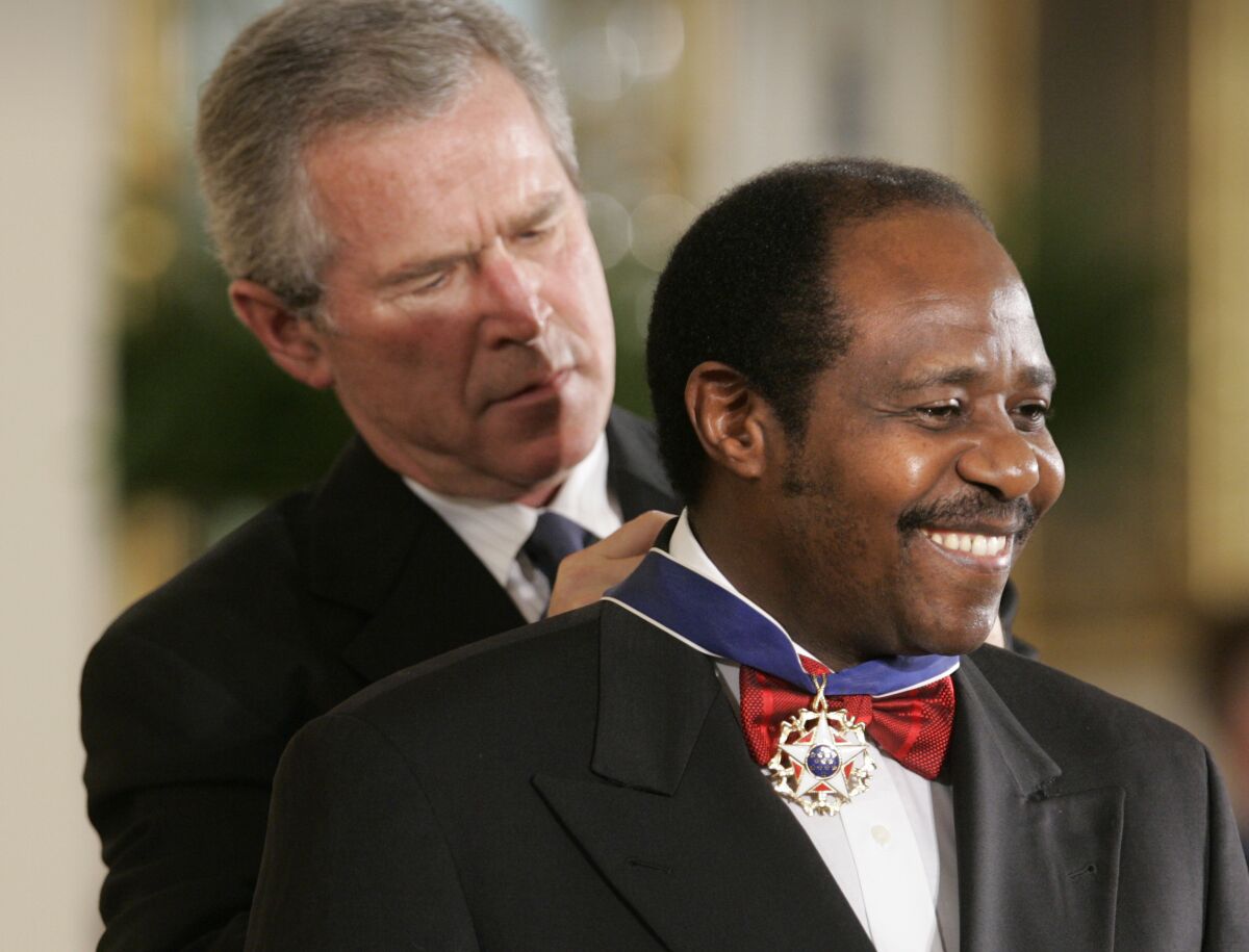 FILE - In this Wednesday, Nov. 9, 2005 file photo, President Bush awards Paul Rusesabagina, who sheltered people at a hotel he managed during the 1994 Rwandan genocide, the Presidential Medal of Freedom Award in the East Room of the White House, in Washington. Rusesabagina, who was portrayed in the film "Hotel Rwanda" as a hero who saved the lives of more than 1,200 people from the country's 1994 genocide, and is a well-known critic of President Paul Kagame, has been arrested by the Rwandan government on terror charges, police announced on Monday, Aug. 31, 2020. (AP Photo/Lawrence Jackson, File)
