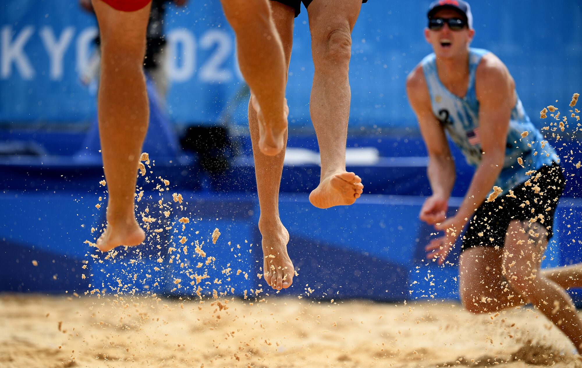 Tri Bourne runs across the sand behind two sets of airborne legs.