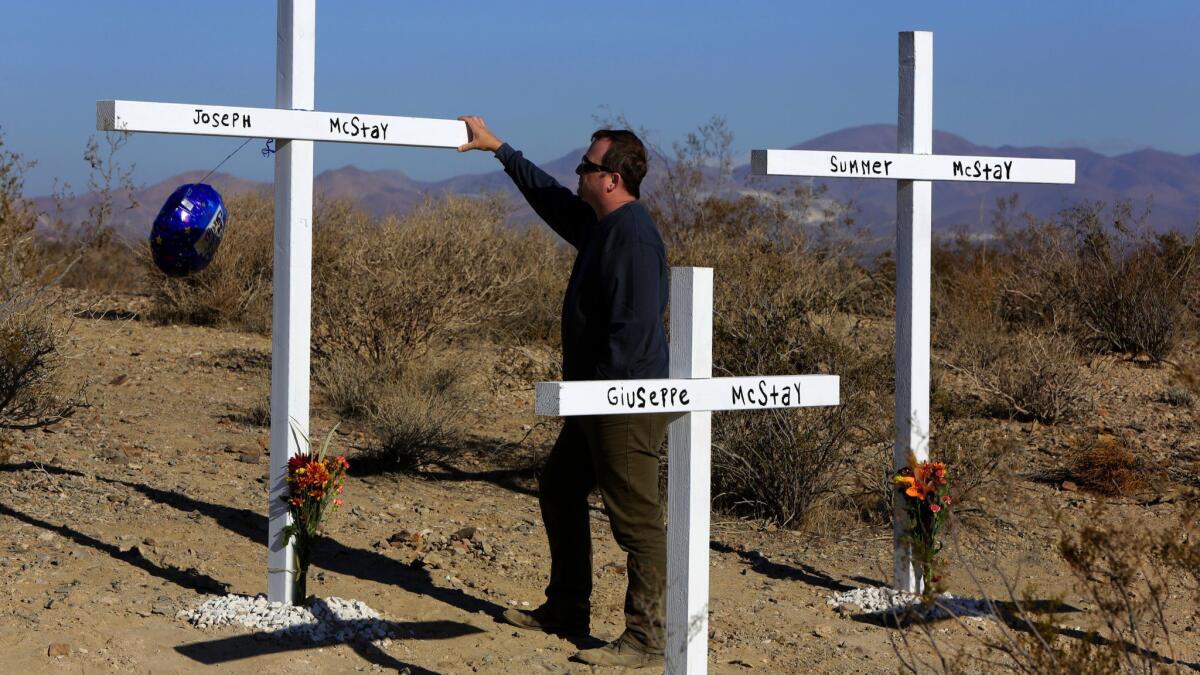 Michael McStay pays his respects to his brother Joseph at crosses erected in memory McStay, his wife and their two children, who were found buried in shallow graves off Interstate 15 in Victorville in 2013.